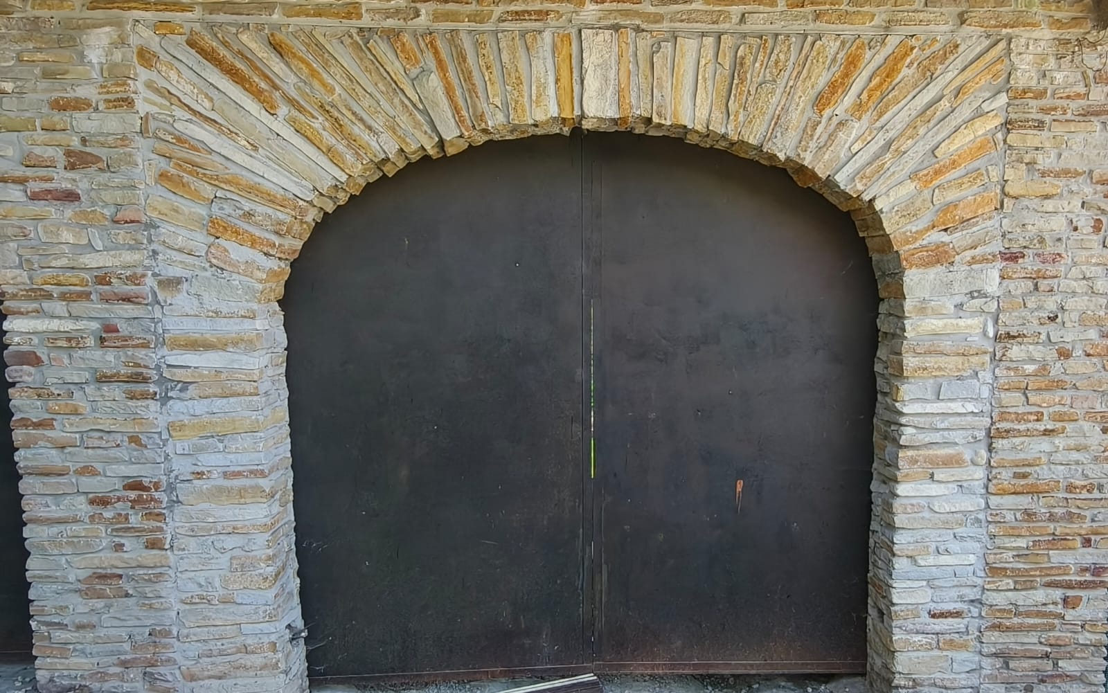 Arco in pietra a tutto sesto con conci chiari e ocra che incorniciano un portale — restauro nelle Langhe firmato Barbero