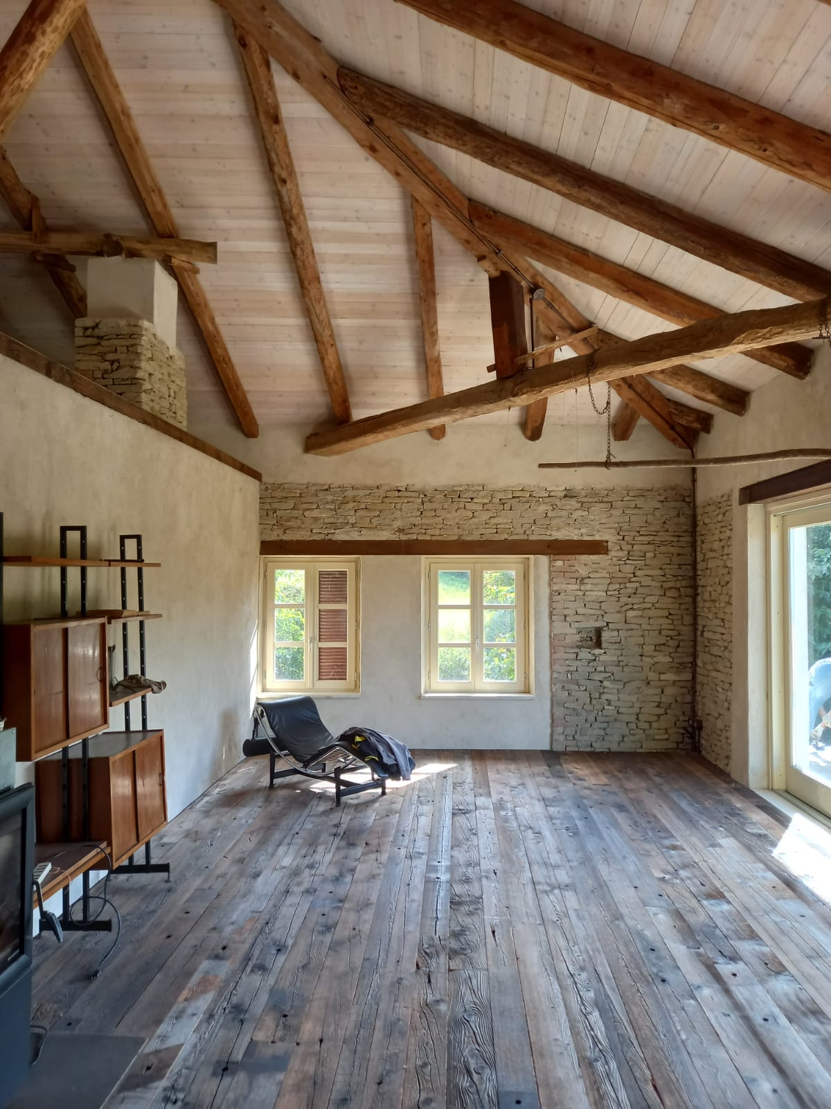 Restauro interno di cascina di Langa con parete in pietra a vista, travi in legno antico e parquet recuperato — realizzazione Barbero