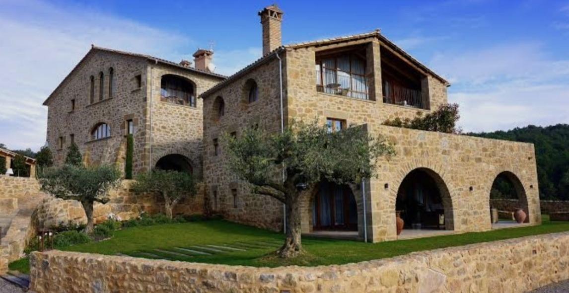 Villa rivestita in pietra irregolare dorata con arcate e ulivi nel giardino — realizzazione Barbero nelle Langhe